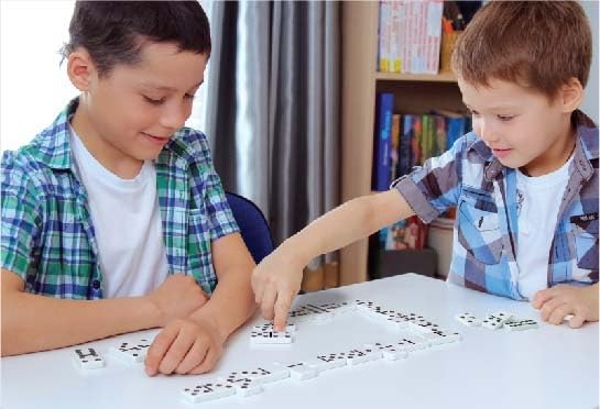 Playzokids Ambassador MA Classic Games Dominoes set with black and white tiles on a wooden surface.
