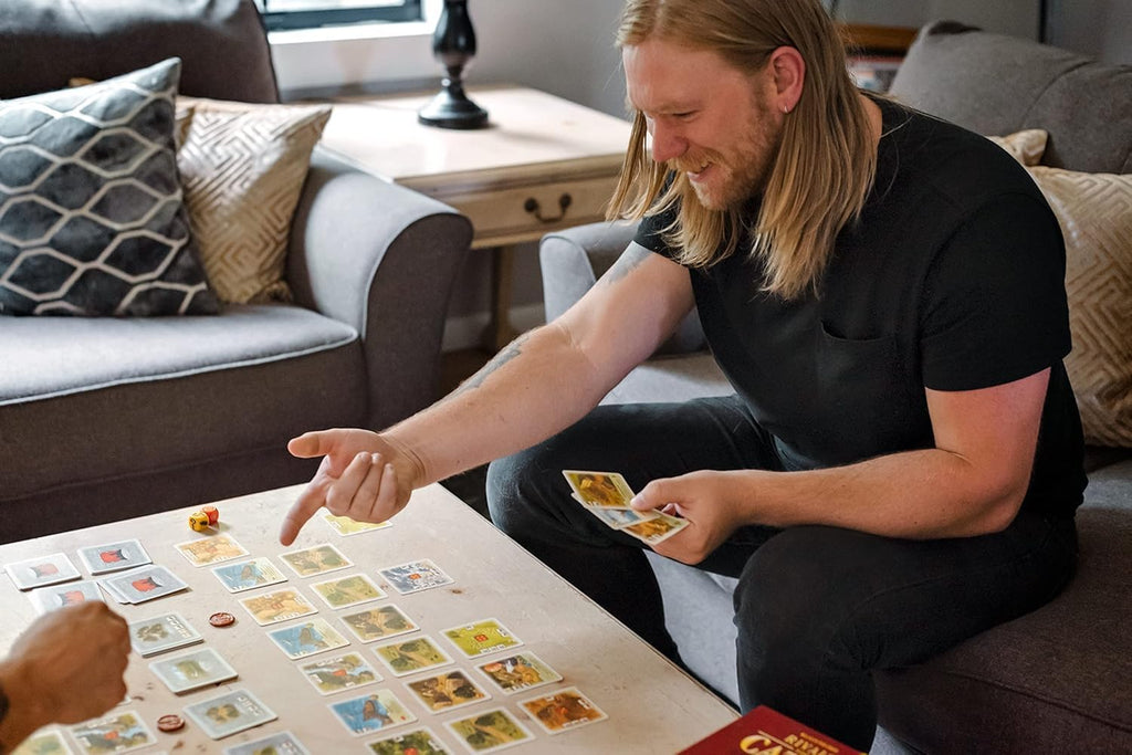 Catan Rivals board game by Playzokids featuring colorful game pieces and cards for 2 players, ages 10 and up, with a game board.