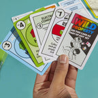 Hasbro Monopoly Deal card game with colorful playing cards and game components laid out on a white surface.